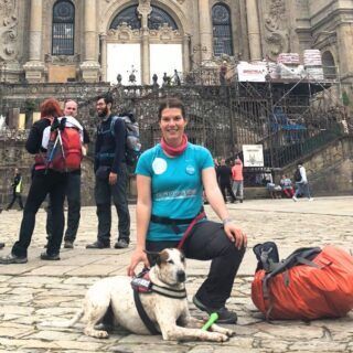 Una chica y un perro, frente a la Catedral De Santiago, acaban de finalizar el Camino De Santiago