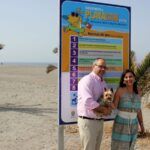 Un hombre, una mujer y un perro en una playa canina